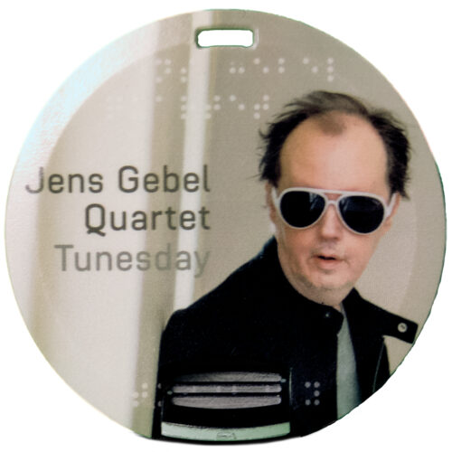 Bild eines runden USB Sticks mit aufgedrucktem CoverFoto Jens Gebel Quartet Tunesday, Jens Gebel mit weisser Sonnenbrille blickt nach vorne.